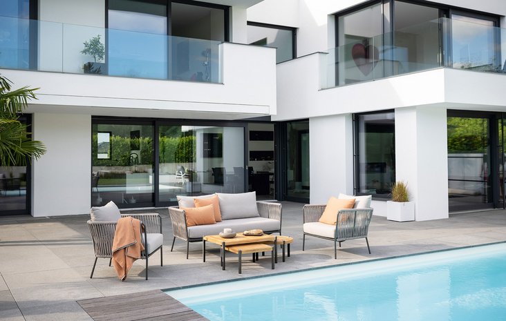 Loungemöbel am Pool Moderner Außenbereich mit Lounge-Möbeln und Kaffeetisch neben einem klaren Pool.