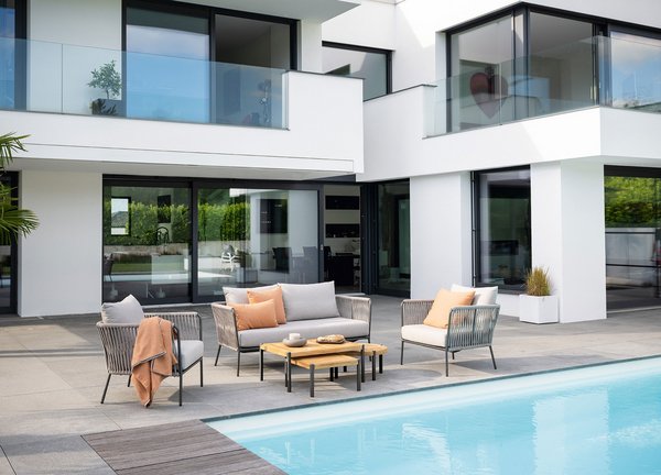 Loungemöbel am Pool Moderner Außenbereich mit Lounge-Möbeln und Kaffeetisch neben einem klaren Pool.