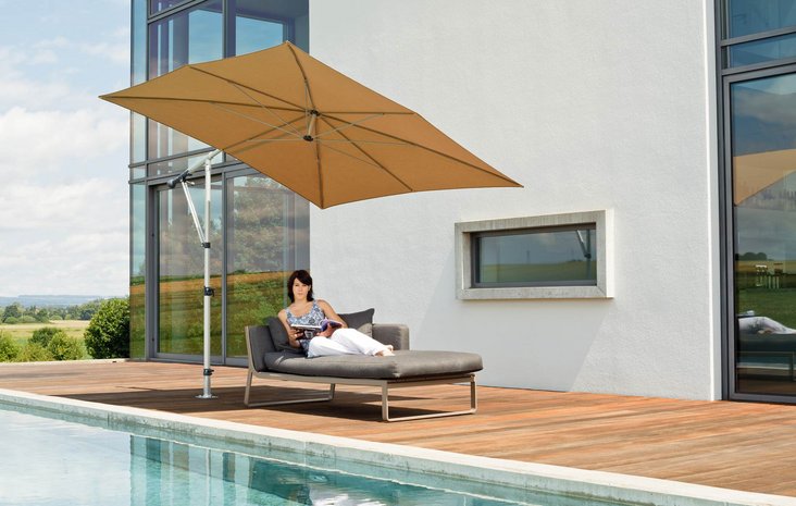 Pool mit Ampelschirm Eine Frau entspannt auf einer Liege neben einem Pool unter einem großen, rechteckigen Ampelschirm an einem modernen Haus.
