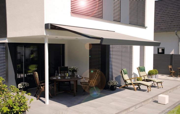 Terrasse mit Markise Moderner Terrassenbereich mit ausfahrbarer Markise, mehreren Liegestühlen und einem runden Tisch.